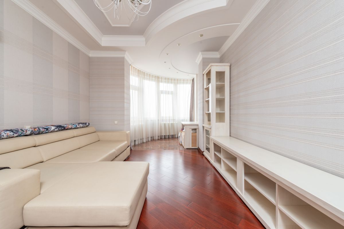 Compact sitting room with a smooth white ceiling, cove detailing, and soft natural light